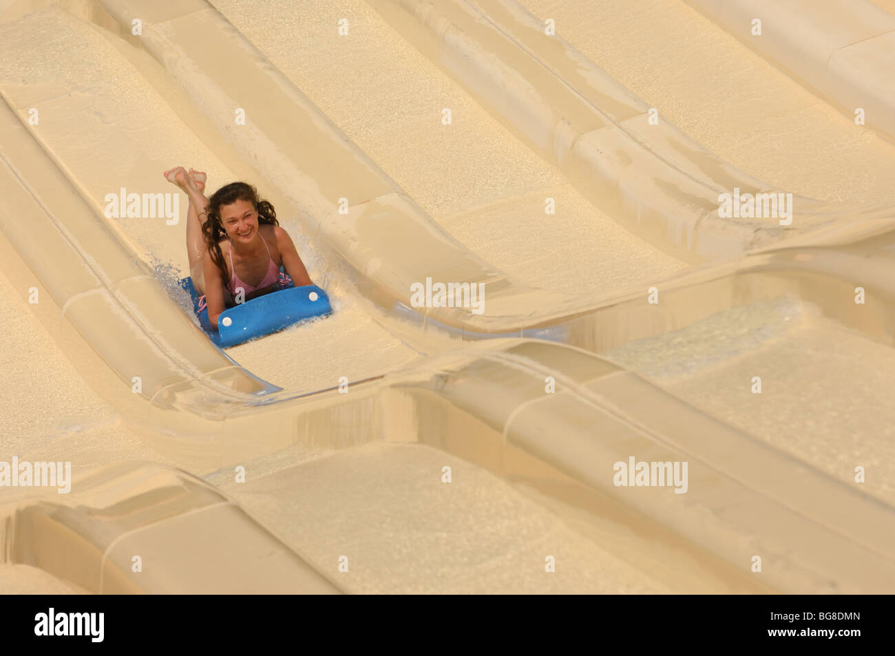 Young laughing woman on a water slide in a waterpark. The image has a ...