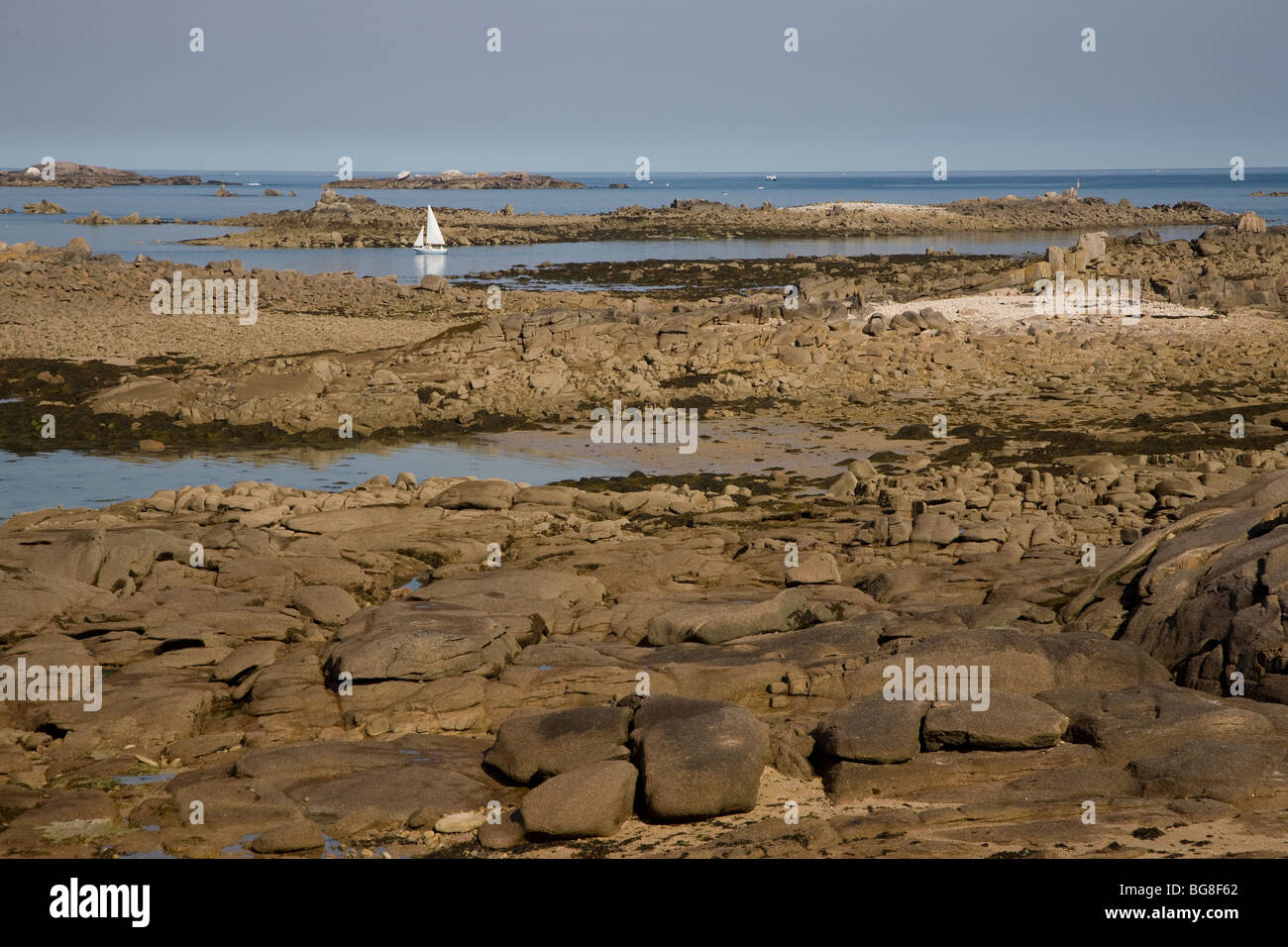 Sailboat in water passage between boulders Stock Photo - Alamy