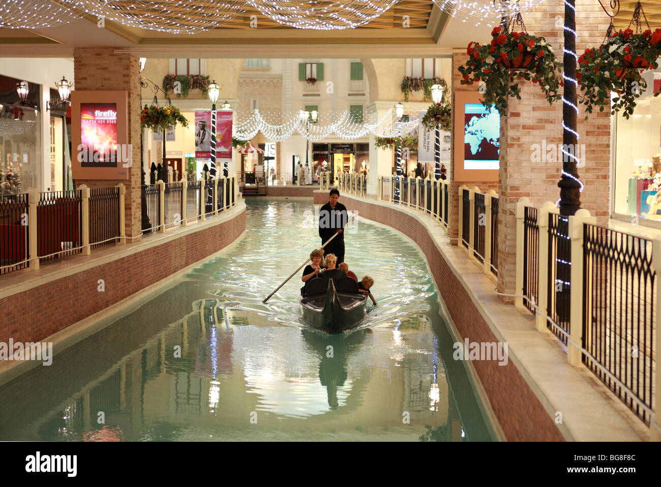 A family enjoy a gondola ride on the artificial river that forms a centrepiece of the Villagio shopping mall in Doha, Qatar Stock Photo