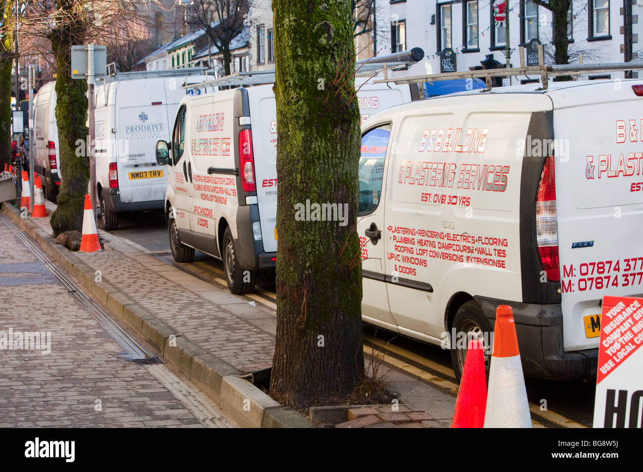 workmans vans that are working on flood damaged shops in Cockermouth Stock Photo
