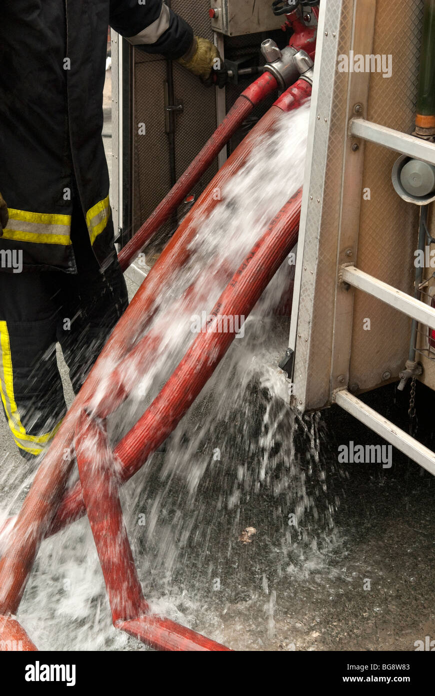 Water gushing from fire hose at fire engine FULLY MODEL RELEASED Stock Photo