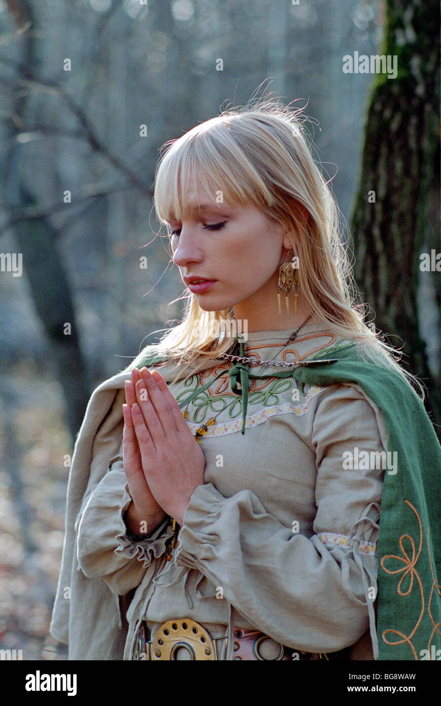 medieval woman praying in forest Stock Photo
