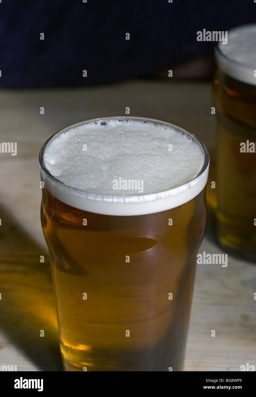 pints of golden amber bitter beer on scrubbed wooden pub table Stock Photo