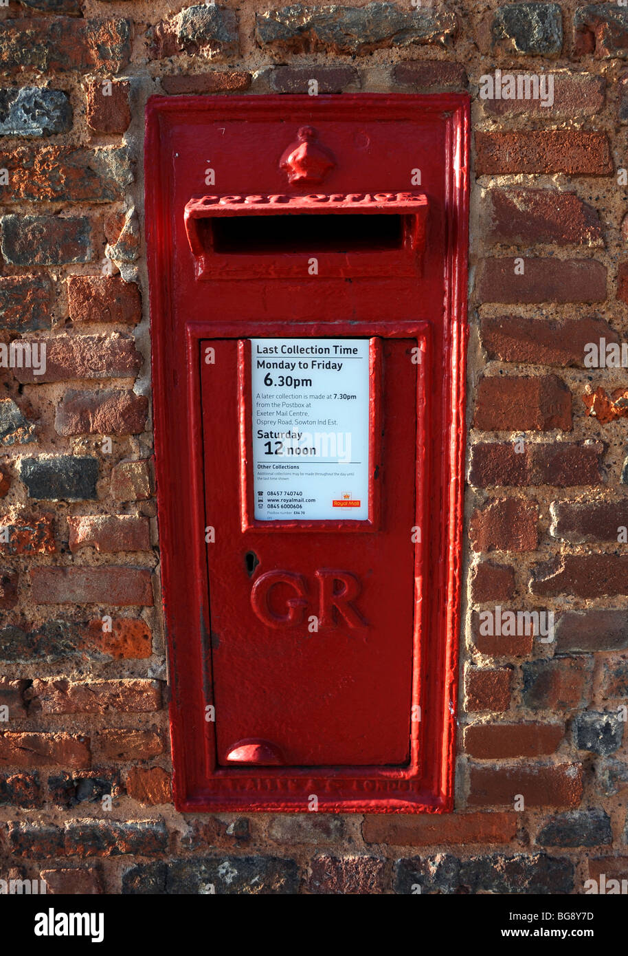 A  red King George VI postbox in a brick wall in exeter Stock Photo