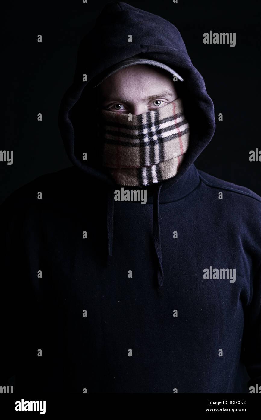 Low Key Shot of a Hooded Chav against a Dark Background Stock Photo