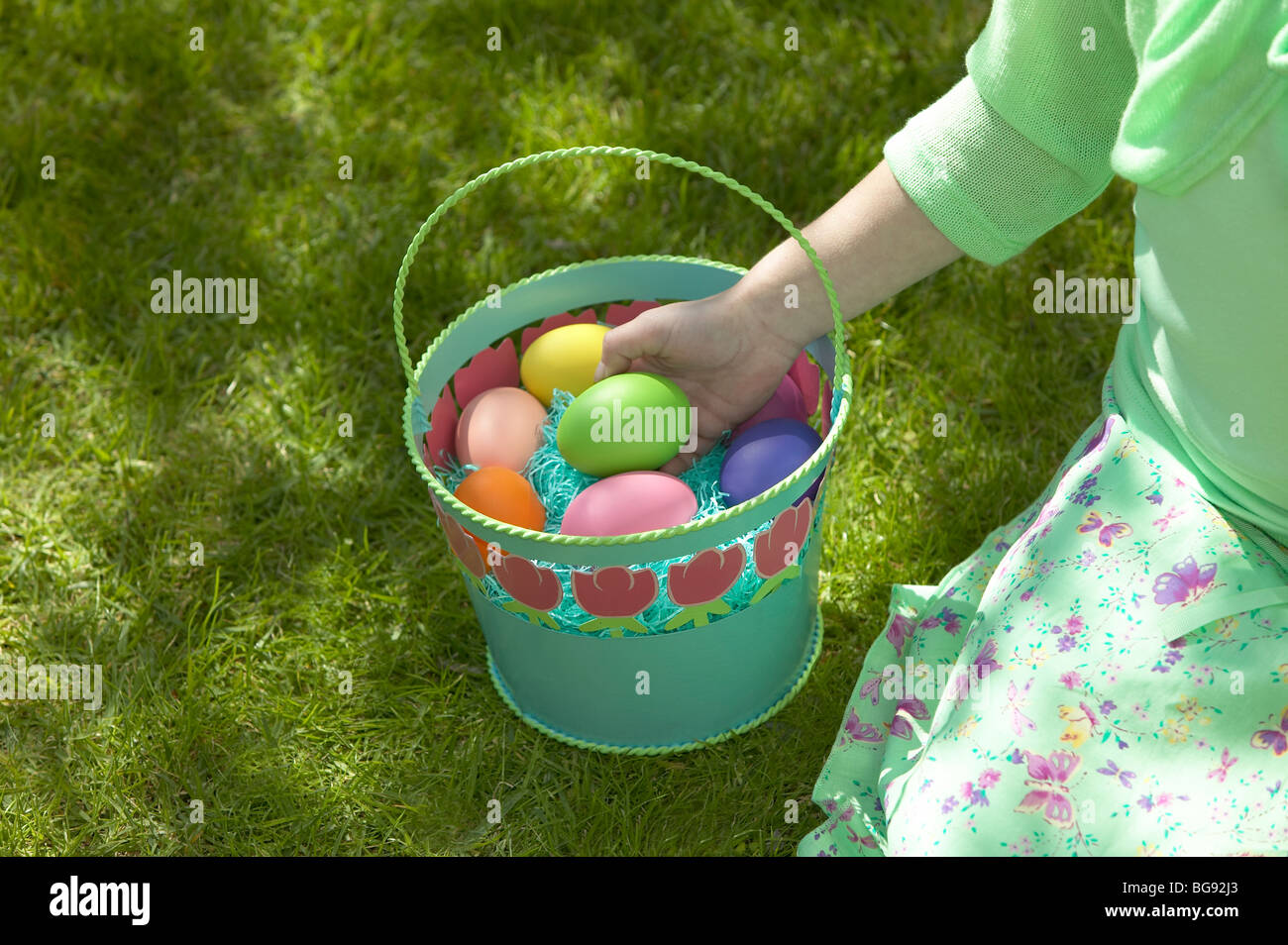 Girl holding Easter egg in basket while sitting on lawn Stock Photo Alamy