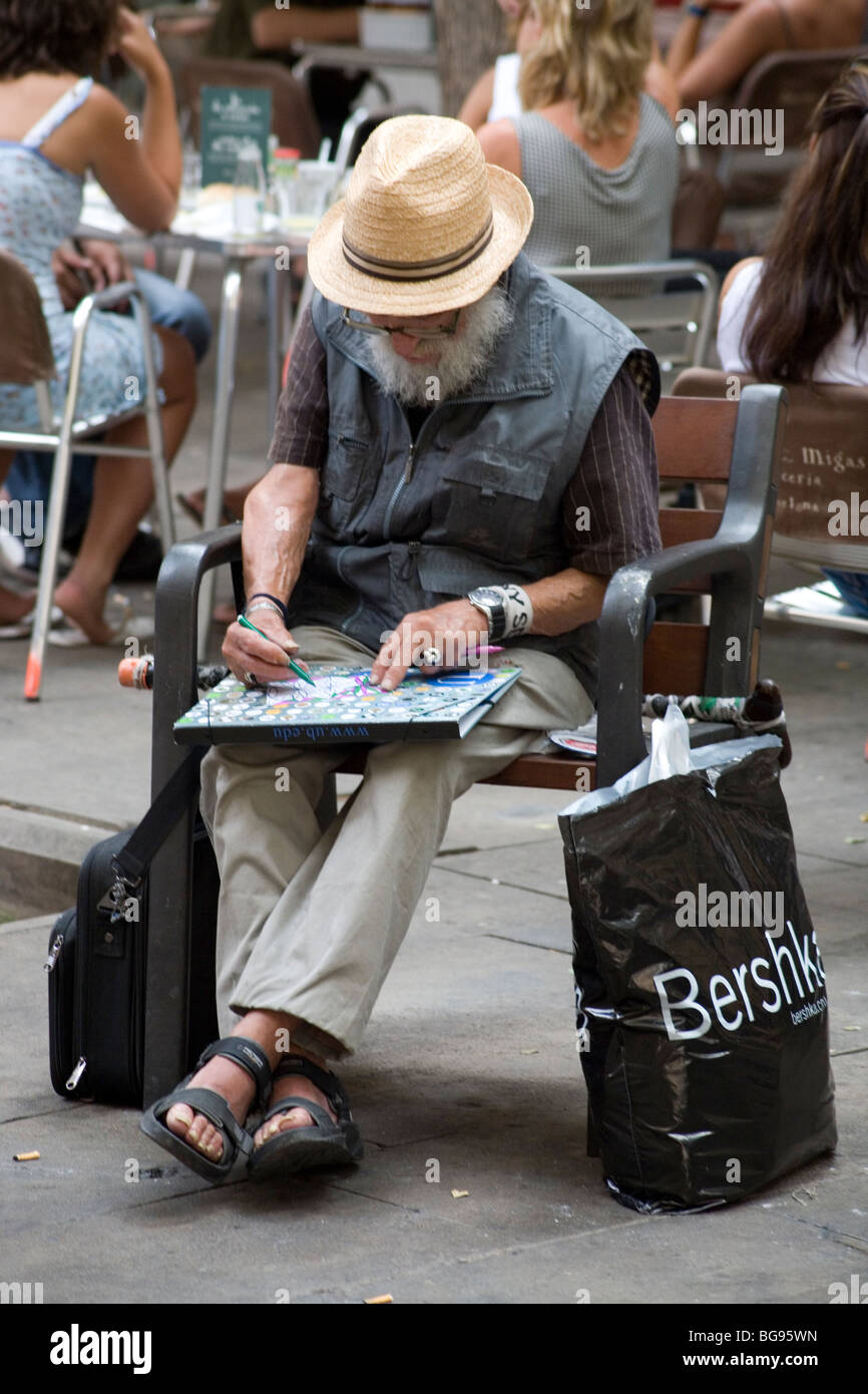 SENIOR, ARTIST, STRAW HAT, DRAWING: An old bearded artist sitting drawing on a bench in a city park Barcelona Catalonia Spain Stock Photo