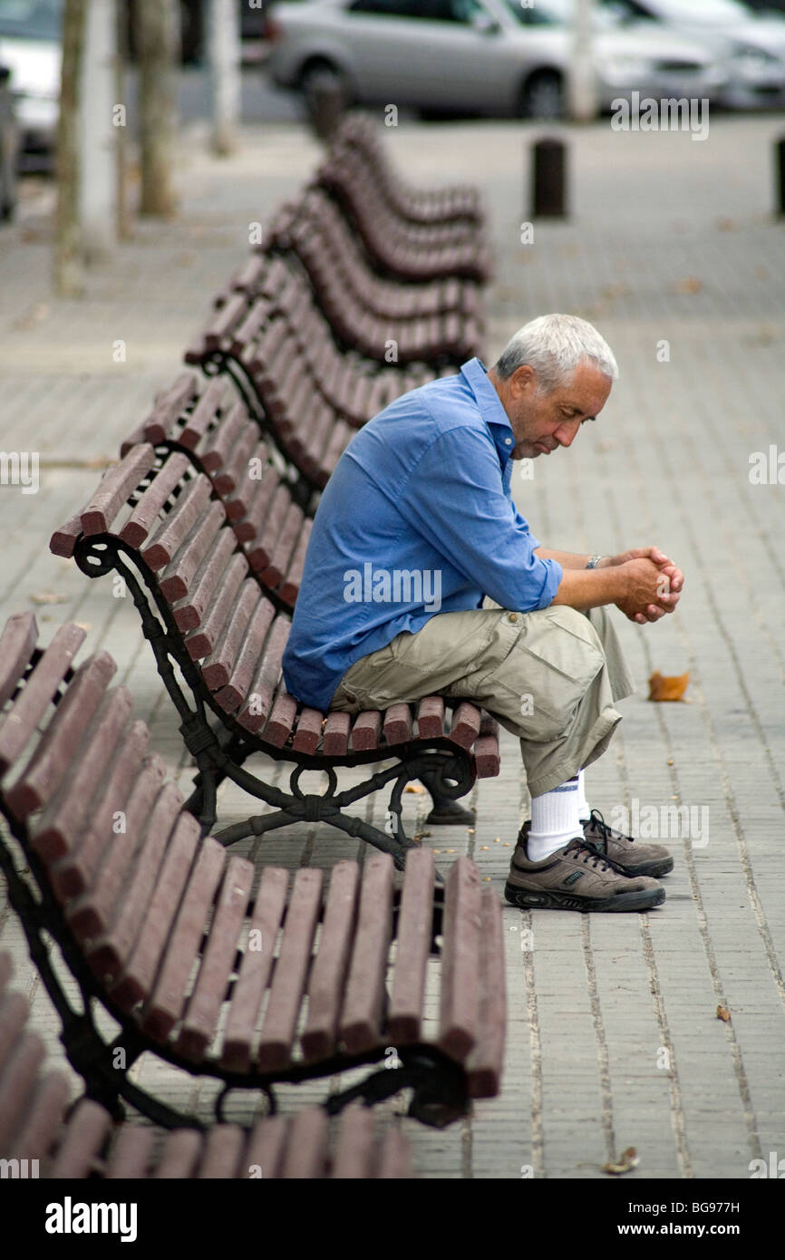 OLD MAN, SIESTA, BARCELONA, THINKING: An old man sitting alone on a bench during siesta in a city park Barcelona Catalonia Spain Stock Photo