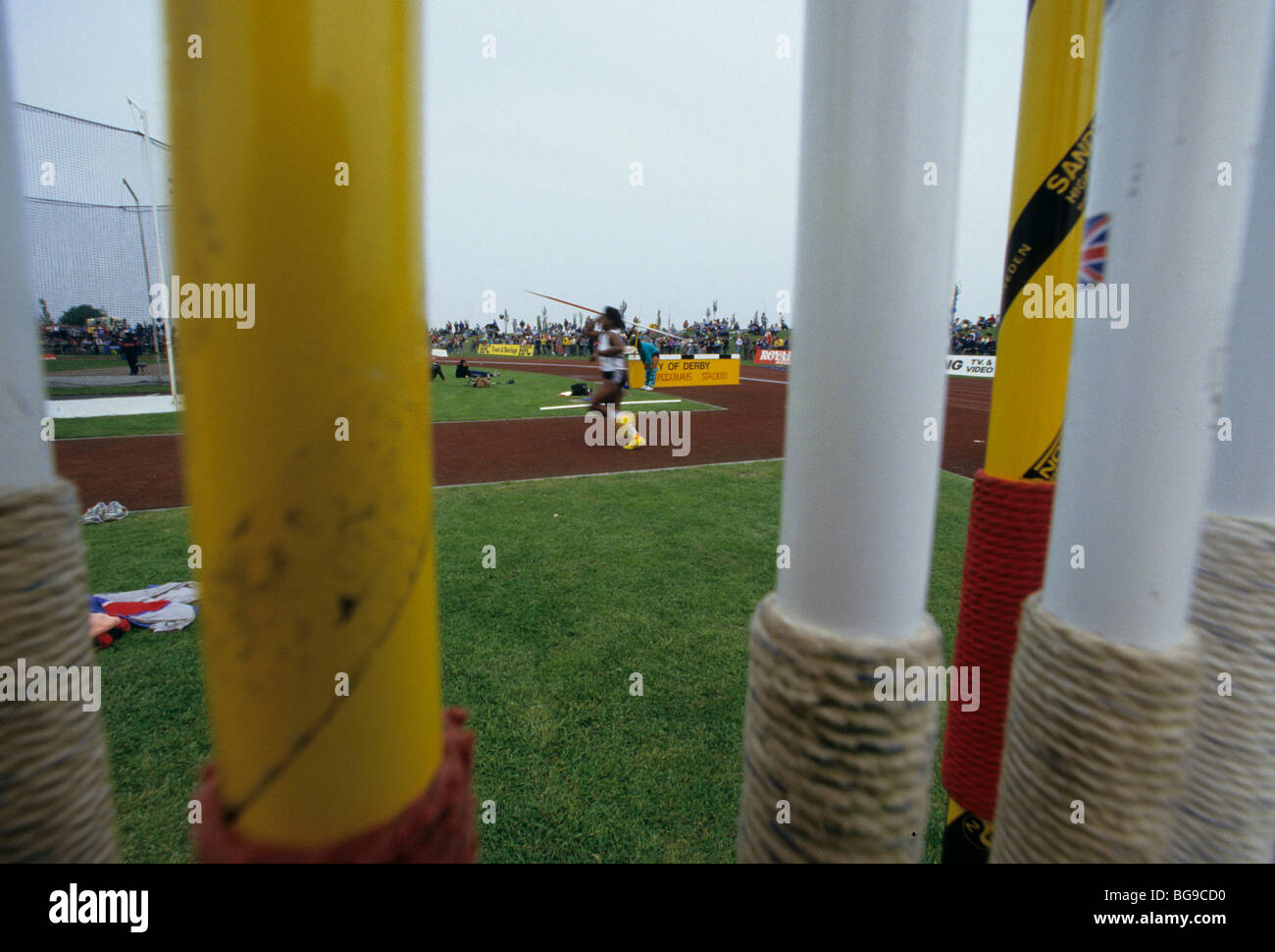 Close up of javelins with athlete throwing javelin in background Stock