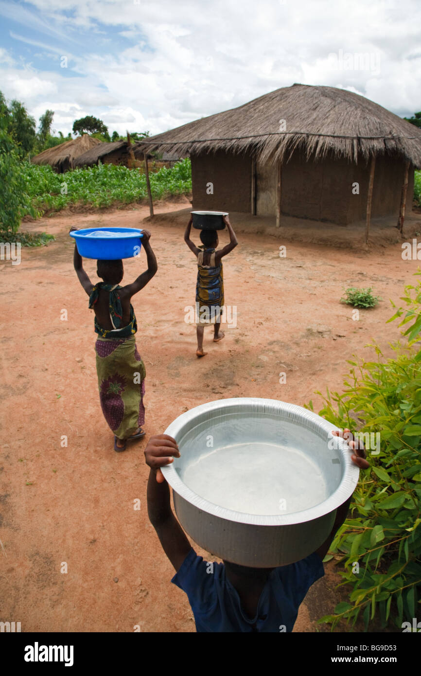 Children carry water to their home from a borehole built by an