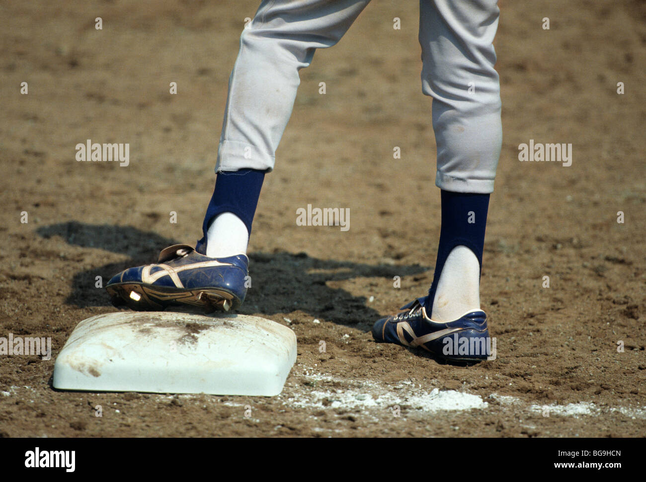 Baseball player standing with foot on base plate Stock Photo