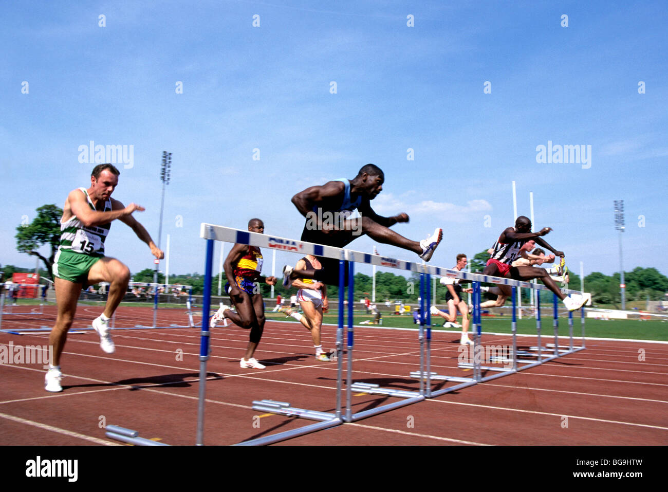 Group of male runners jumping over hurdles Stock Photo Alamy