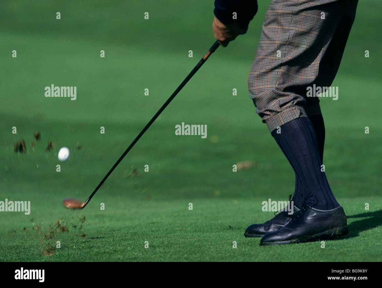Golfer in plus fours striking a ball with a fairway wood Stock Photo