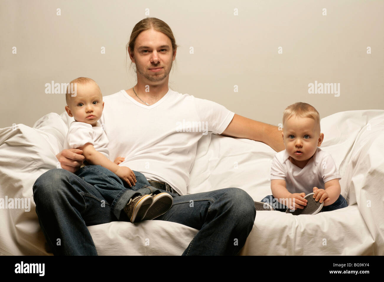 Laughing father sitting on a couch with boy twins Stock Photo