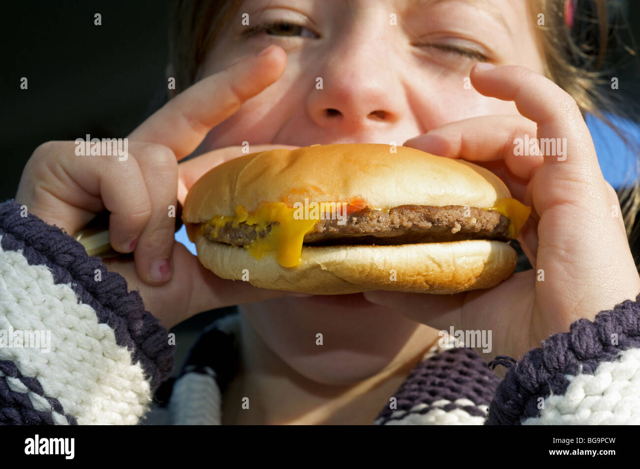 Young girl eating a Mcdonald's cheese burger Stock Photo