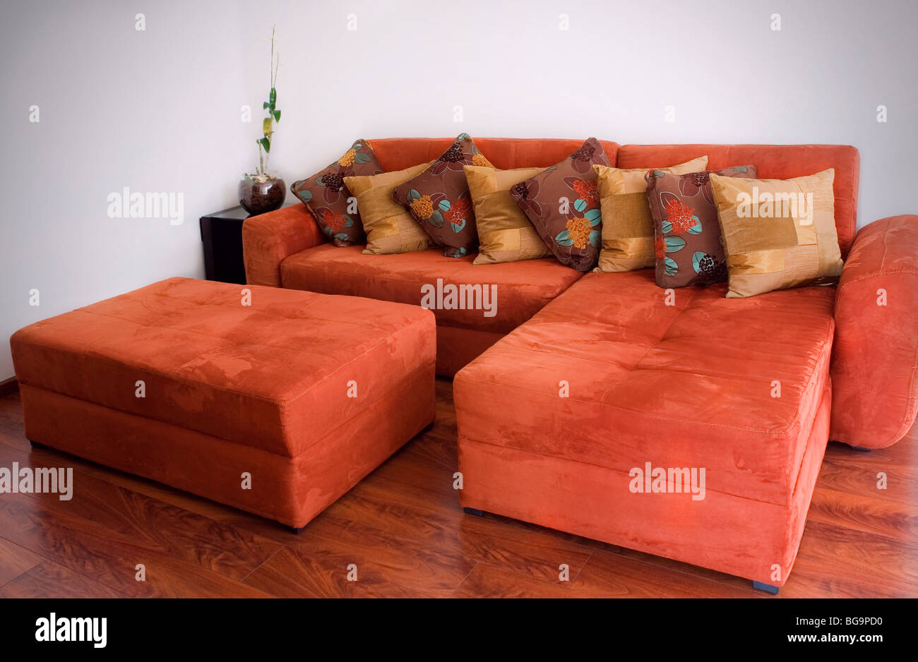 Comfortable orange velvet couch with patterned pillows Stock Photo
