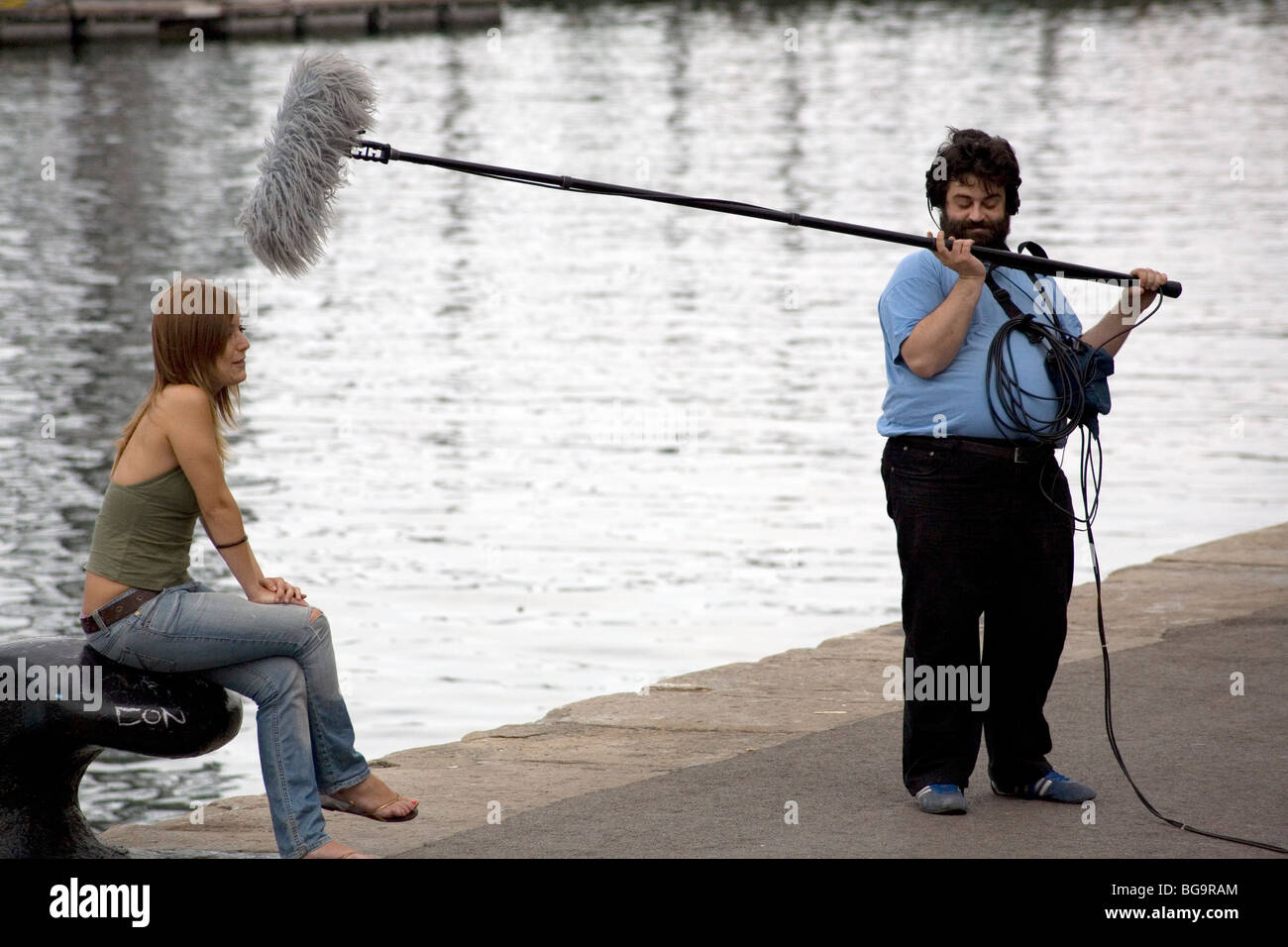 TV SHOW, OUTSIDE BROADCAST, SOUND BOOM: TV crew outside broadcast harbour sound boom microphone presenter in Barcelona Harbour Spain Stock Photo