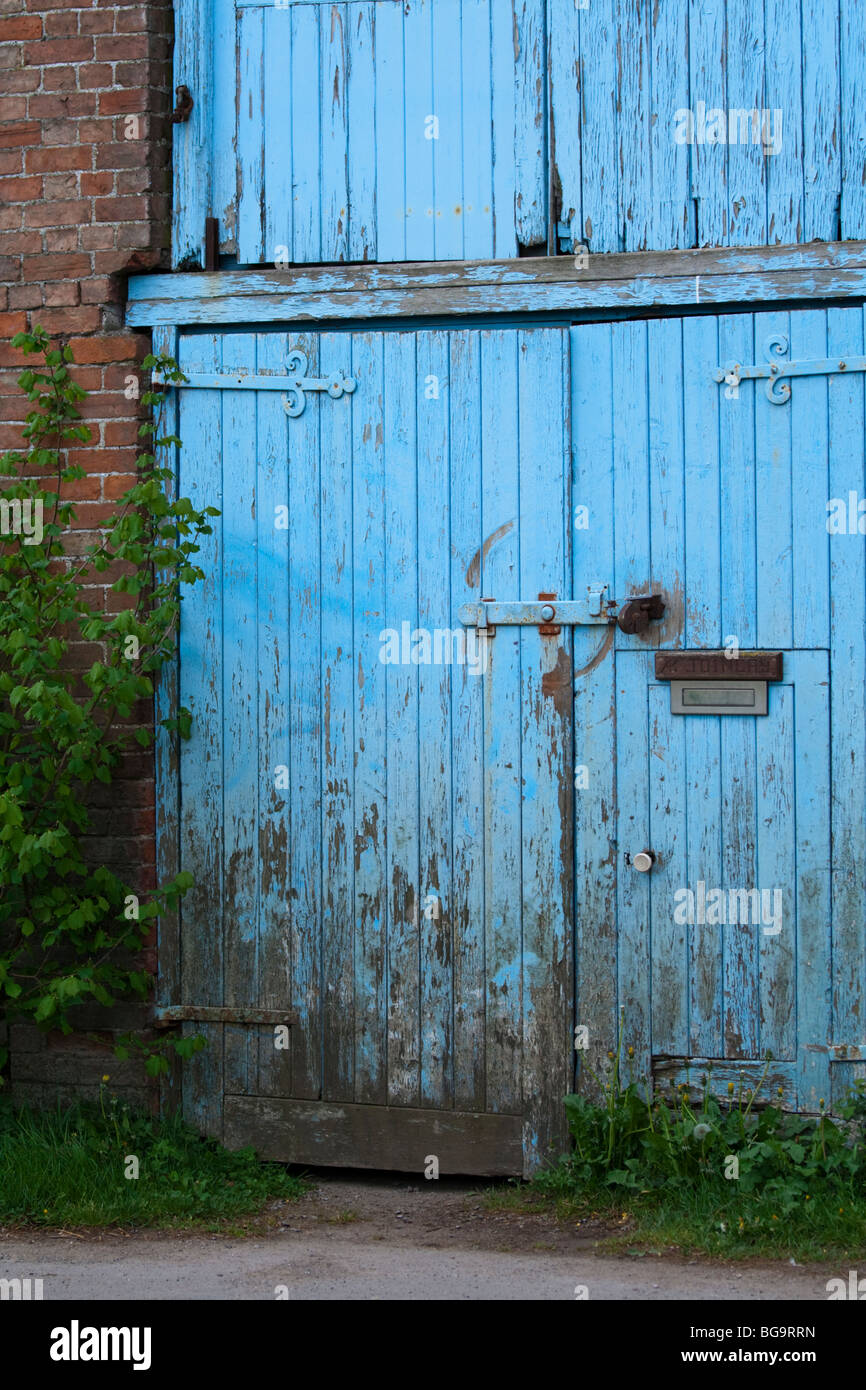 Segments of a run down garage with peeling blue paint, broken windows and rotting wood. Stock Photo