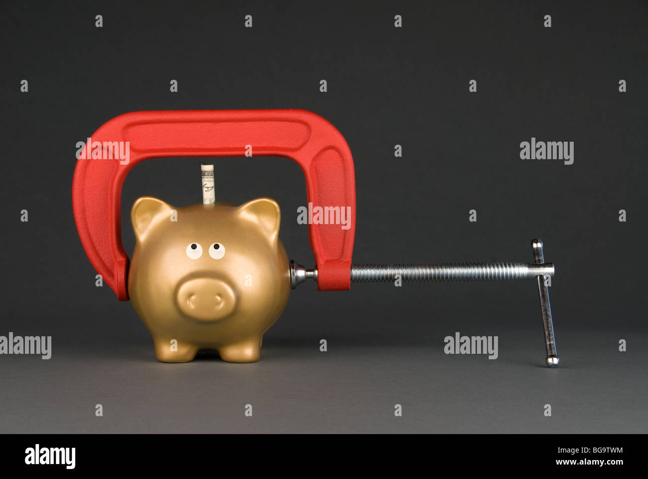 A golden piggy bank is being squeezed for its last dollar. Image can be used for many financial inferences. Stock Photo