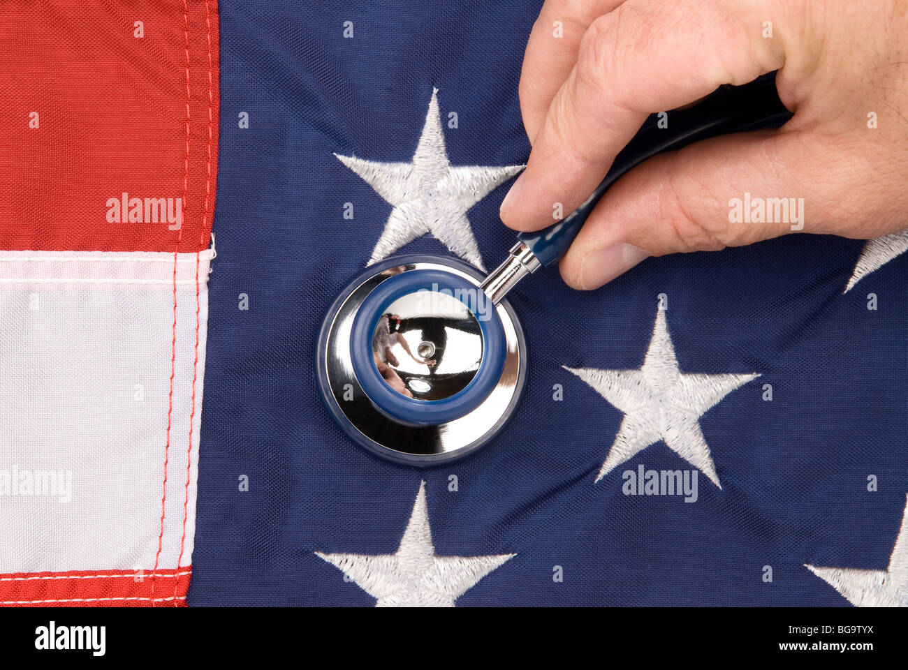 A doctor examines an American flag with a stethoscope. Image can be used for economic or medical inferences. Stock Photo