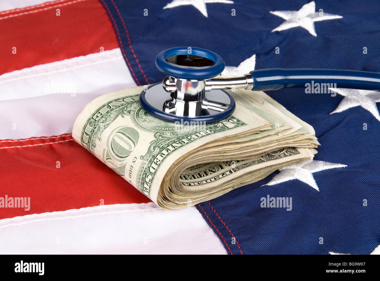 A pile of cash on an American flag with a stethoscope Stock Photo