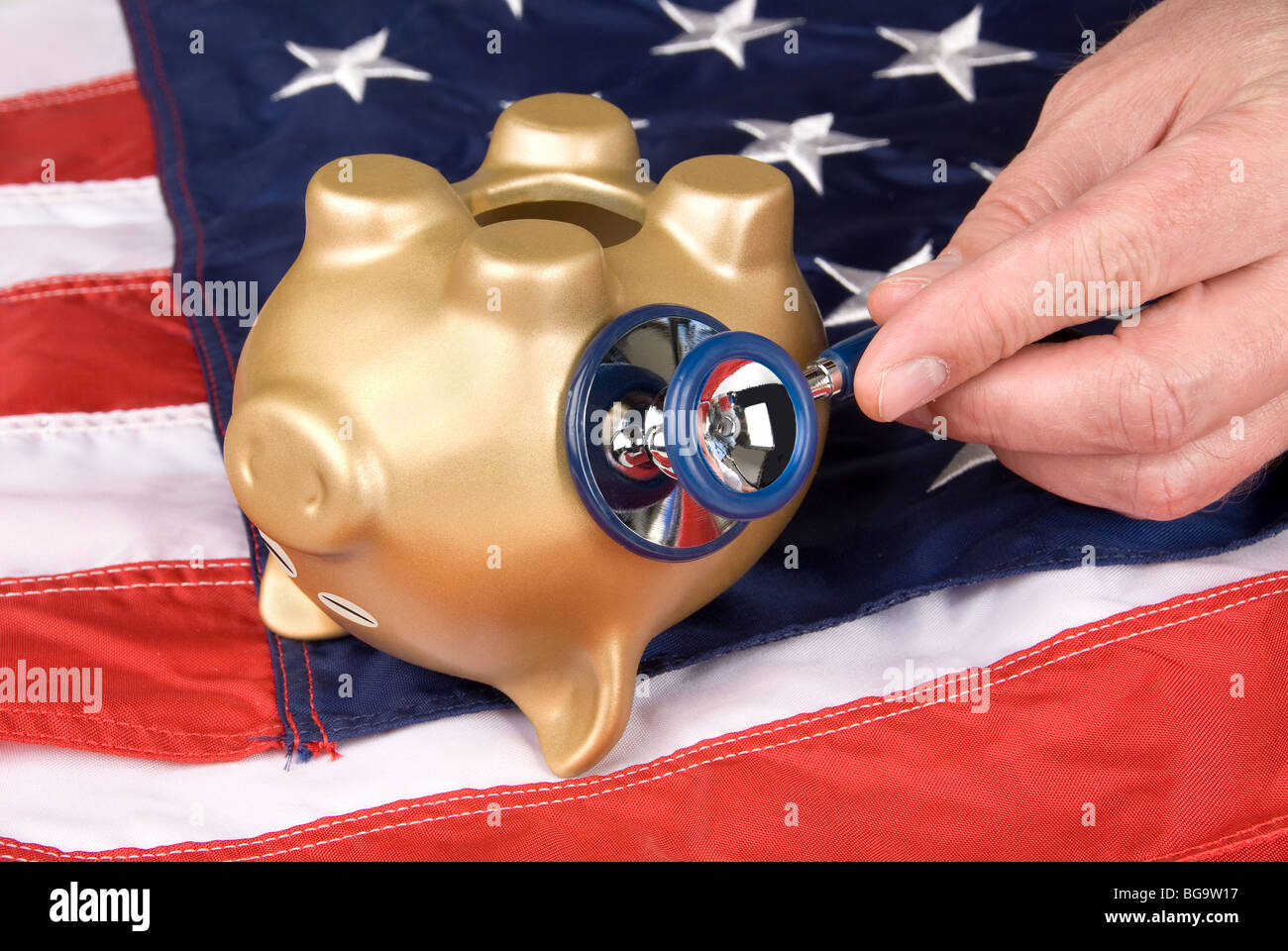 An upside down, nearly dead piggy bank on an American flag is being examined for signs of economic and financial life. Stock Photo