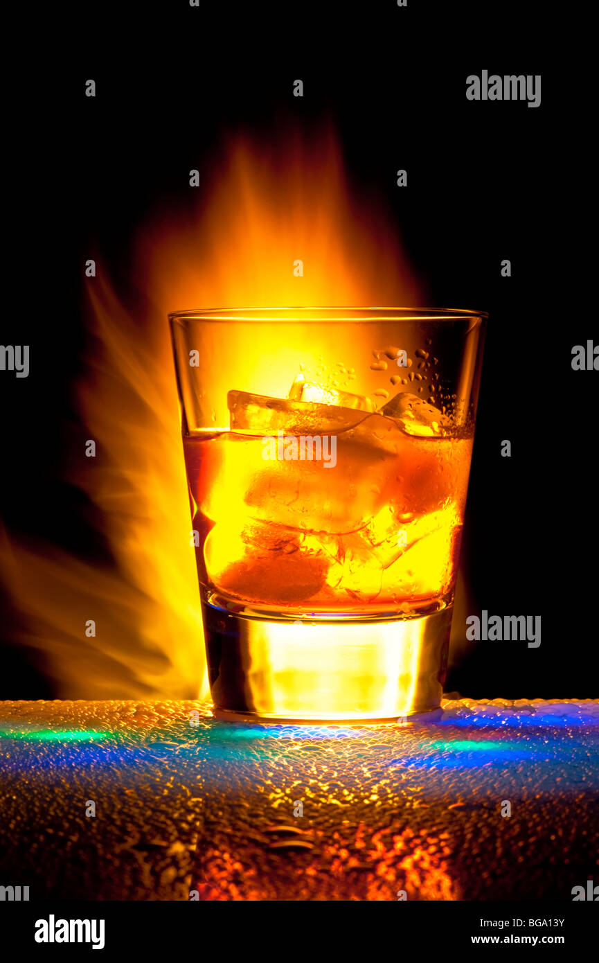 Glass with alcohol against Bengal fires with reflexion, in a glass ice. Against a dark background Stock Photo