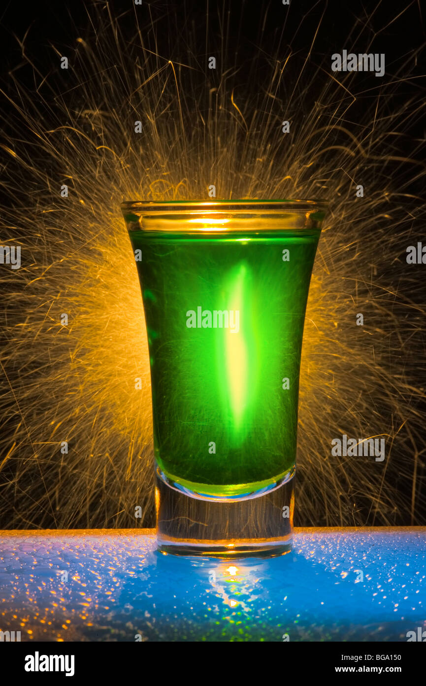 The wine-glass for a cocktail with alcohol of green colour against Bengal fires with reflexion Stock Photo