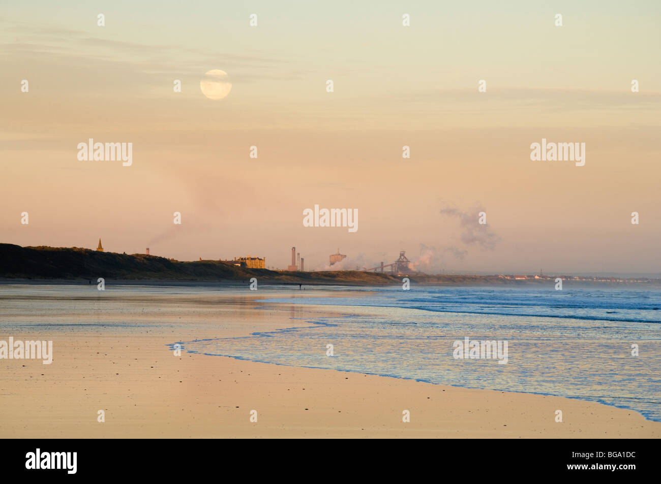 Full moon setting over Saltburn beach with Redcar furnace in the background, Cleveland, England Stock Photo
