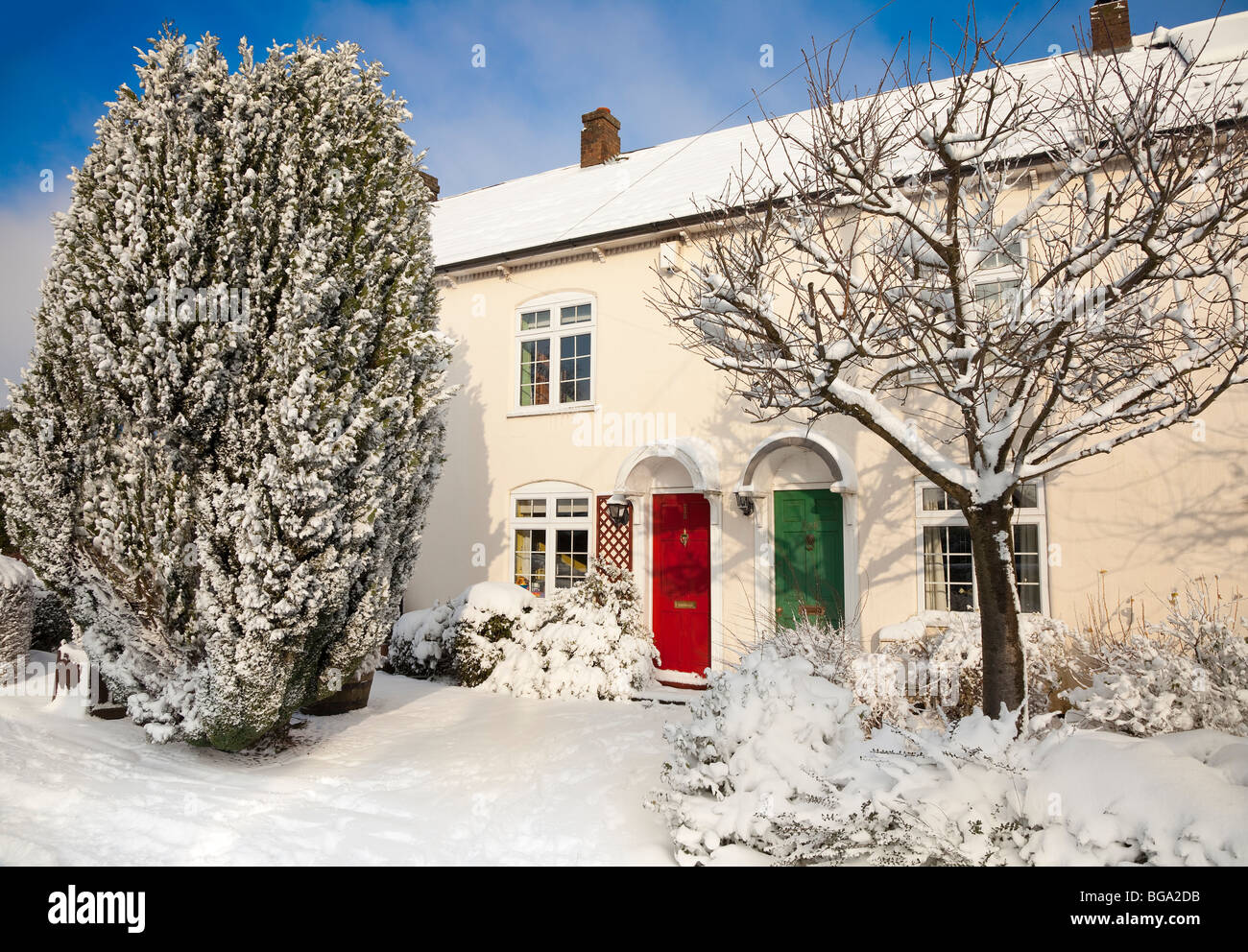 Picturesque village snow scene, Bedfordshire UK, colourful doors, warm winter sun. Stock Photo