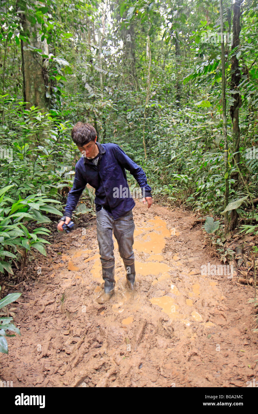 teenage boy walking along a muddy path near Refugio Amazonas, Tambopata National Reserve, Amazon Area, Peru, South America Stock Photo