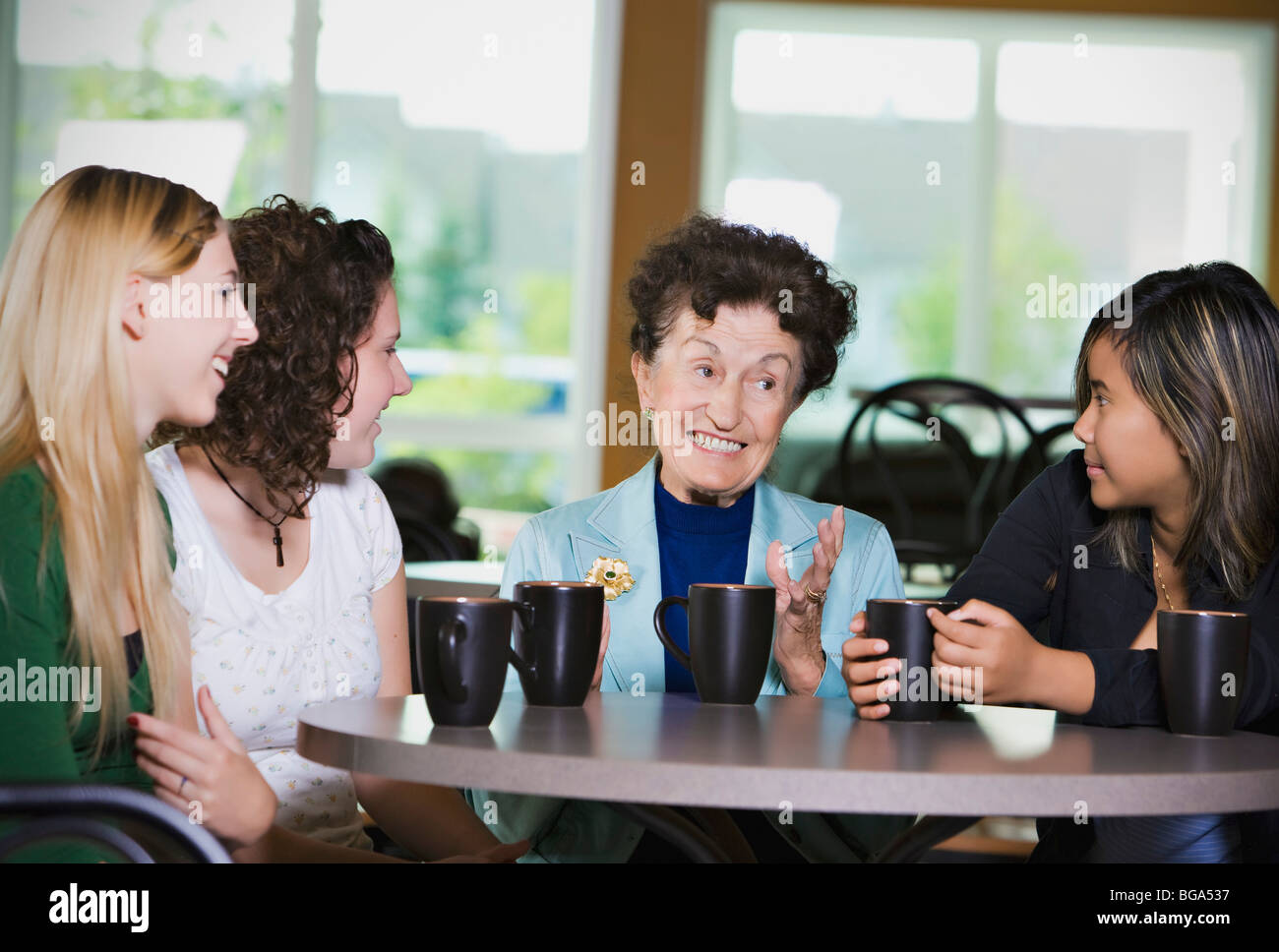 Senior woman chatting over coffee with teenage girls Stock Photo - Alamy