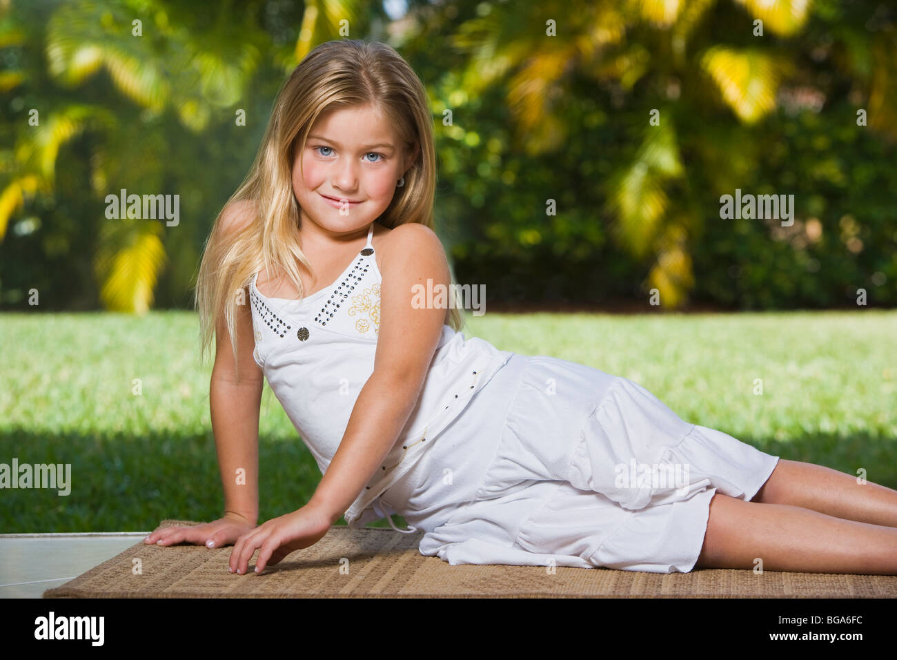 Blond girl laying down on rug, smiling, portrait Stock Photo