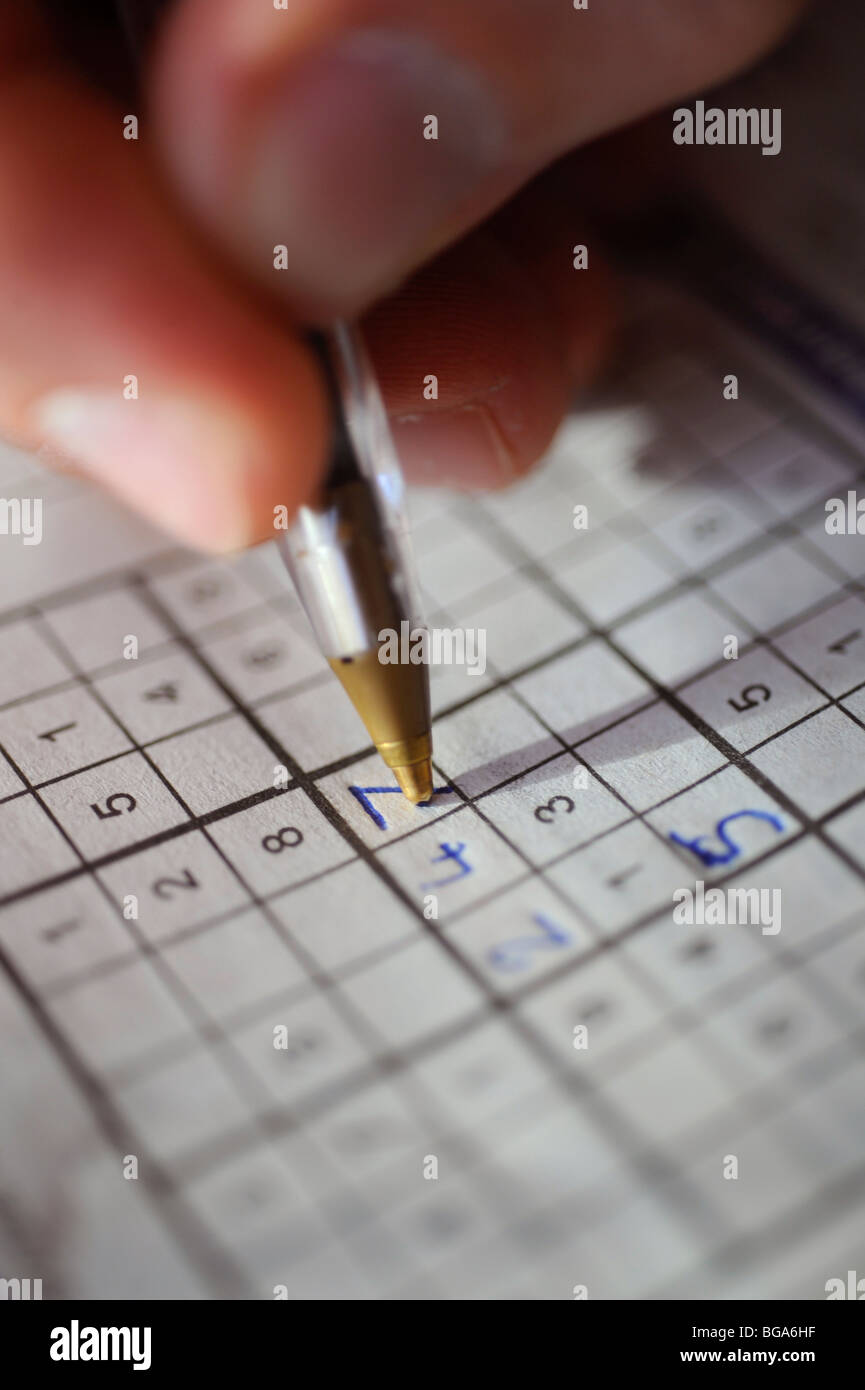 Lucky number 7 a person playing SuDoku writes an answer in one of the squares on a newspaper quiz page. Stock Photo