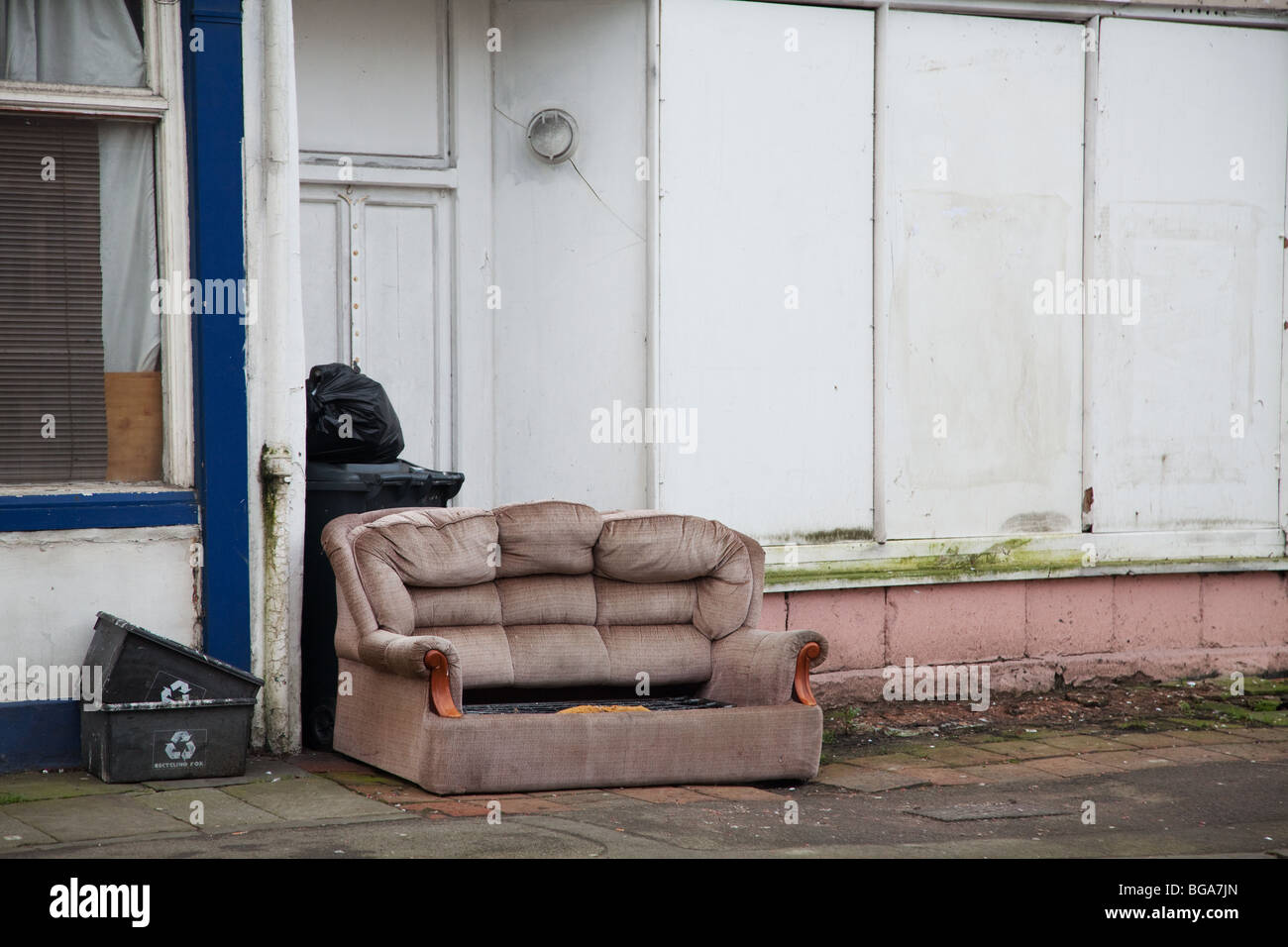 Sofa left outside a boarded up derelict shop Stock Photo Alamy