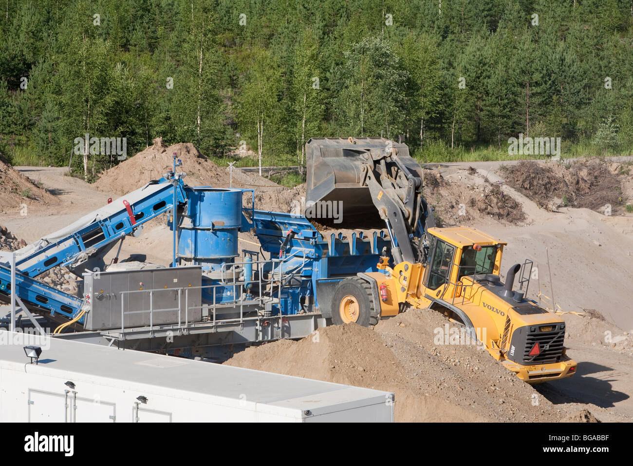 Front loader loading sand and stones to the rock crusher / separator machine , Finland Stock Photo