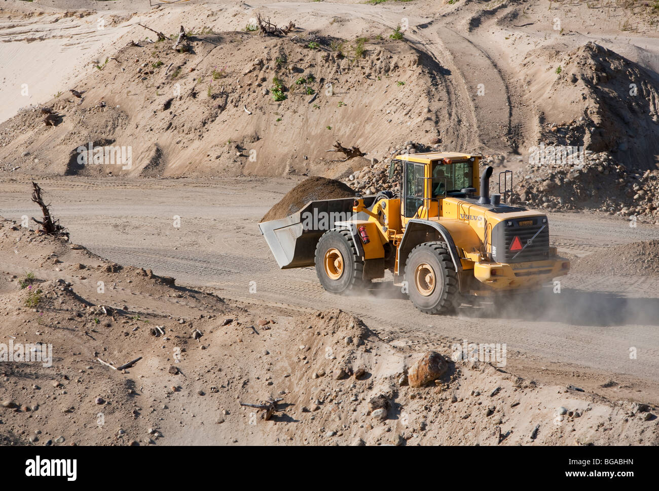 Volvo front loader moving sand in a sandpit at sand quarrying area ...