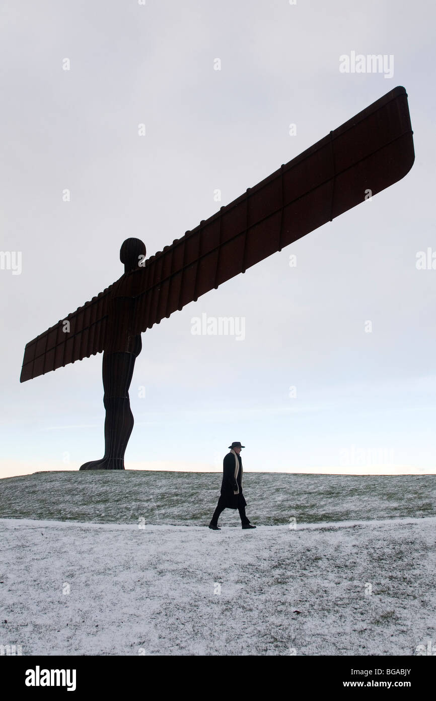 A man walks through snow below The Angel of the North, Antony Gormley's landmark sculpture in north-east England. Stock Photo