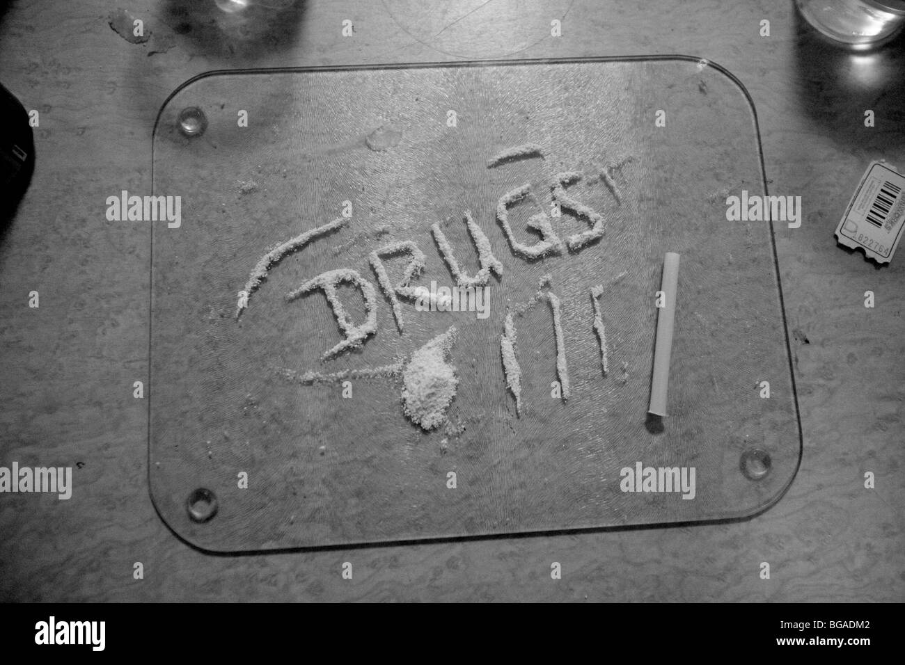 Powdered narcotic (mephedrone MCAT) on a glass plate spelling out the word drugs. Stock Photo