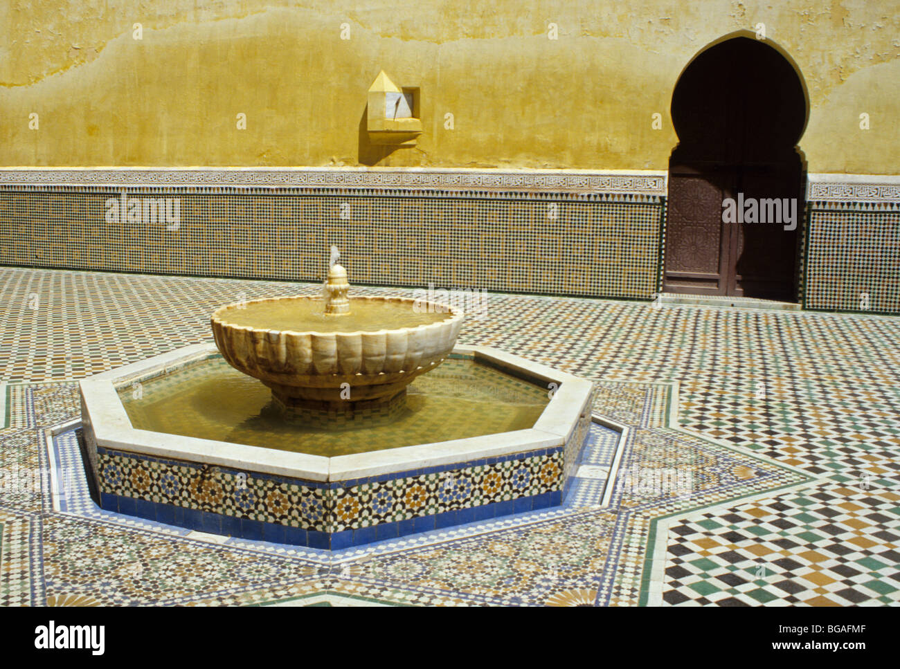 Meknes, Morocco.  Courtyard of the Mausoleum of Moulay Ismail, with Horseshoe Arch Doorway, Sun Dial, and Fountain. Stock Photo
