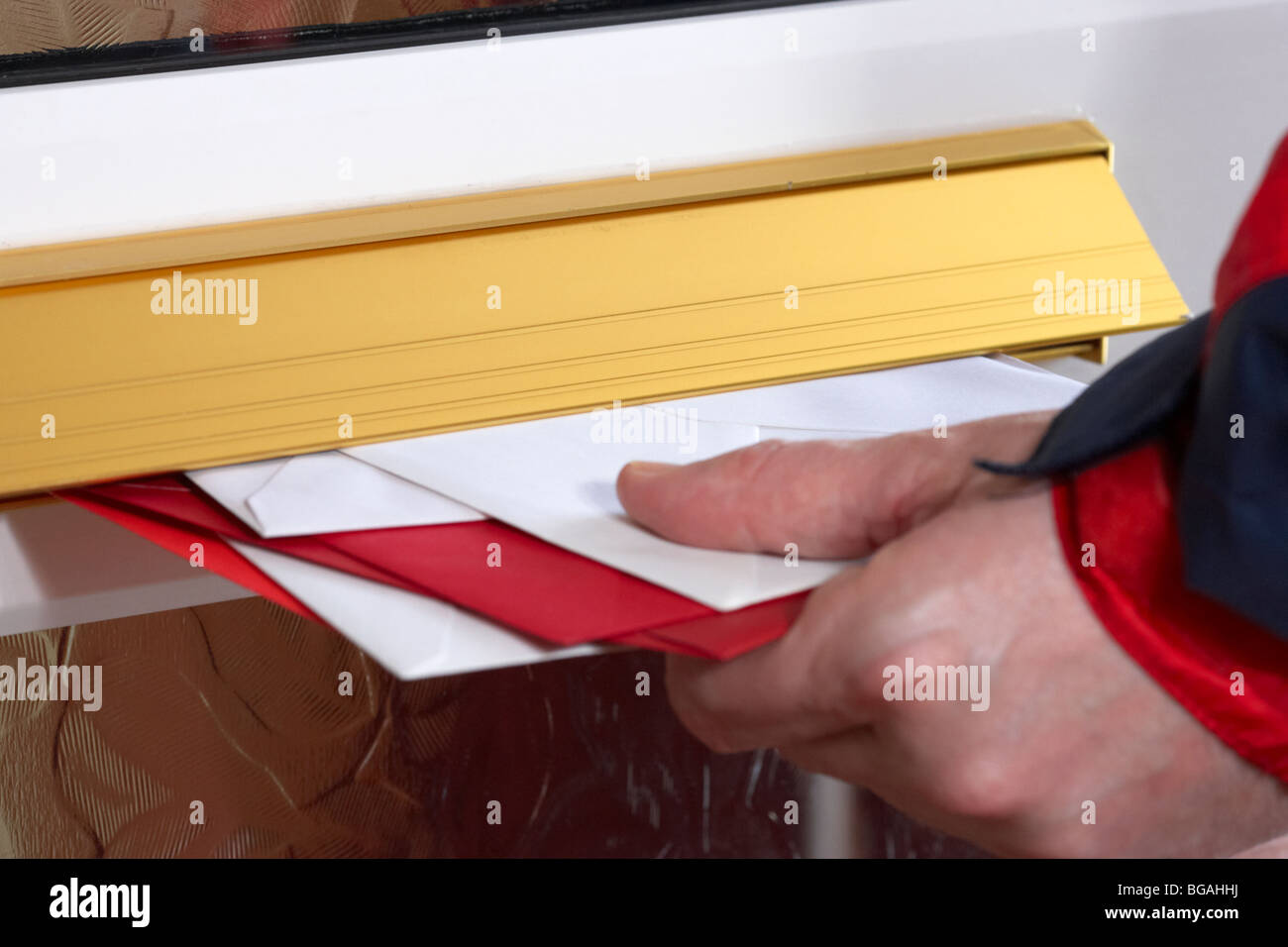 postmans hand pushing letters and cards into the letterbox of a house in the uk Stock Photo