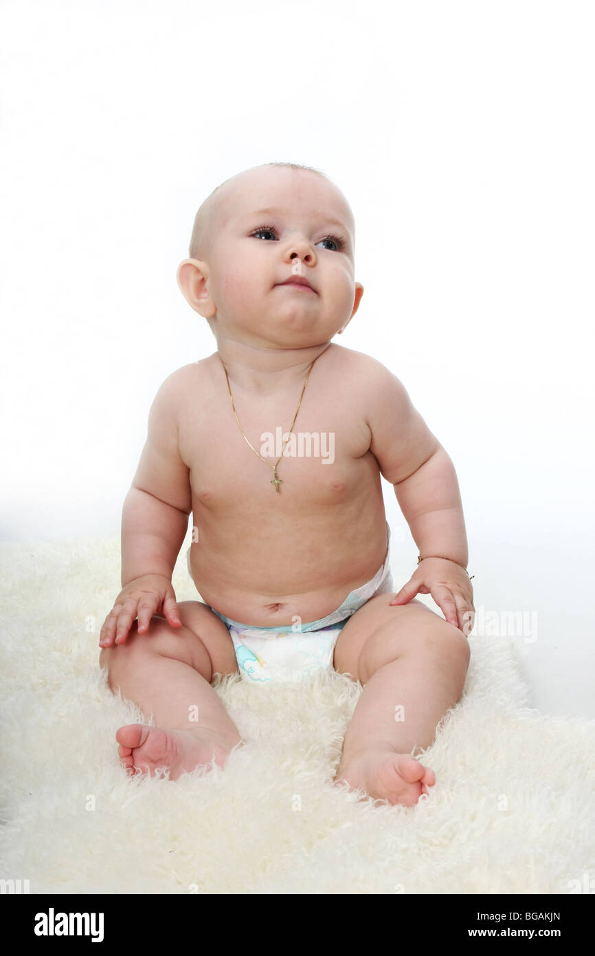 A young child sitting on rug, white background Stock Photo - Alamy