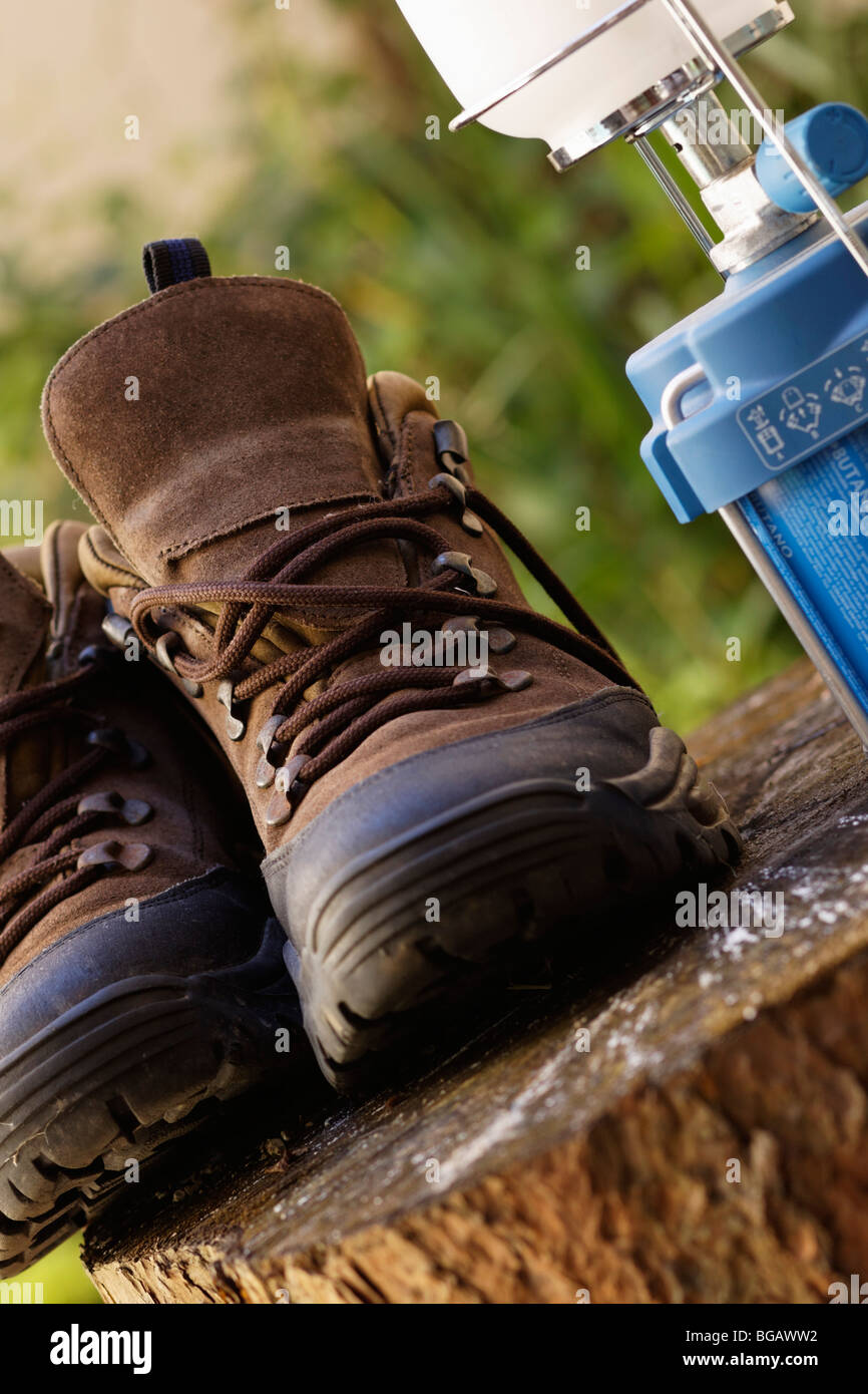 Conceptual depiction of outdoor activity showing gas lamp and a pair of hiking boots placed on a tree stump. Stock Photo