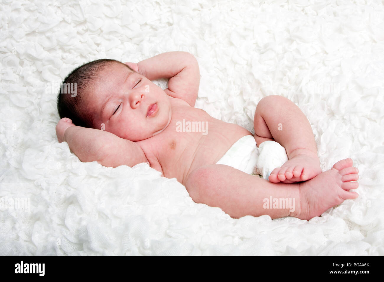 Cute Caucasian Hispanic infant baby asleep on soft white cotton cloud, wearing only a diaper. Stock Photo