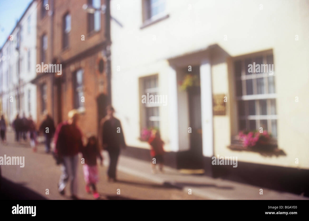 Impressionistic view of street with painted and brick terrace houses in sunlight with family walking towards viewer Stock Photo