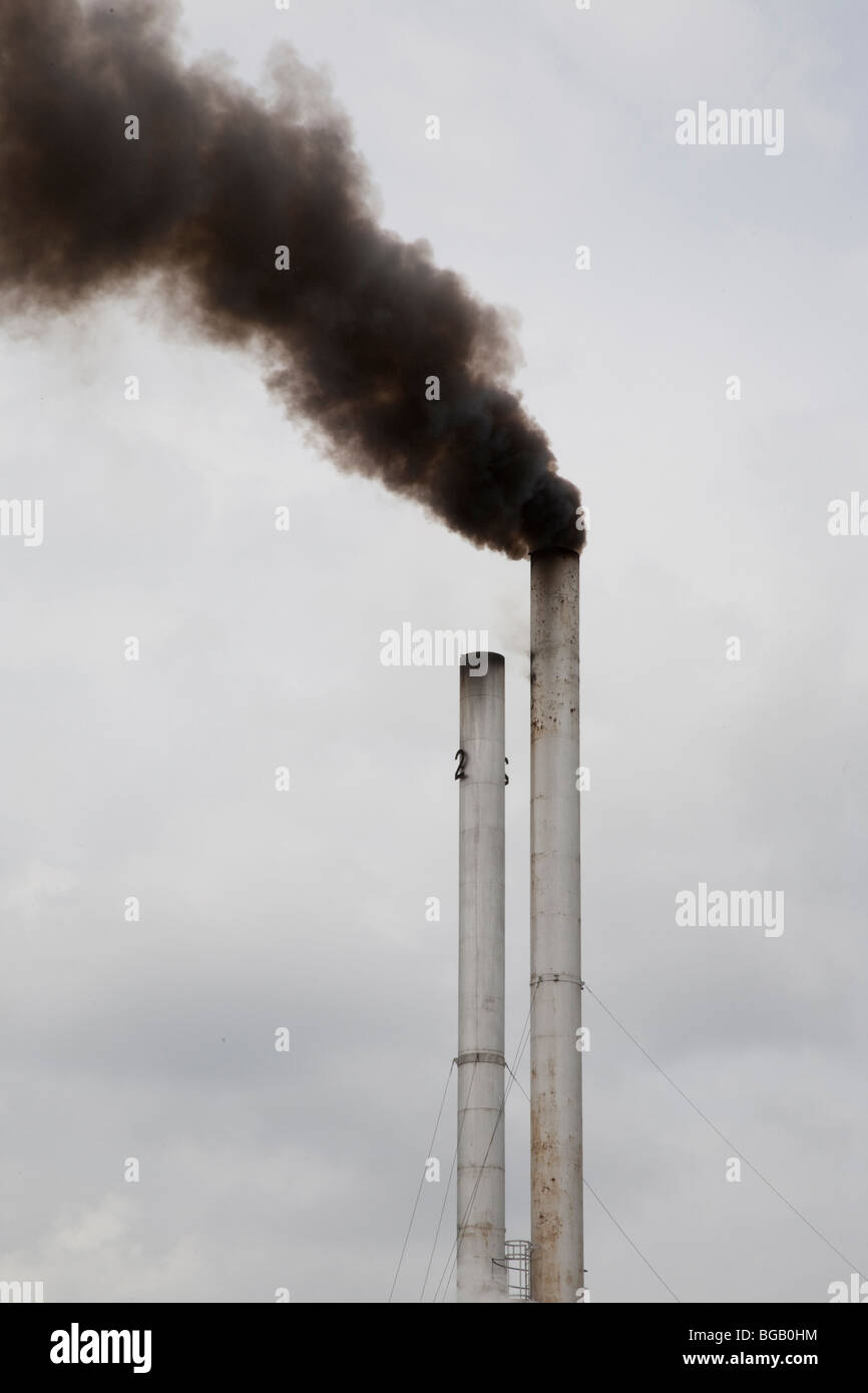 Black smoke emerging from a tall stack at the palm oil mill. The Sindora Palm Oil Mill, Malaysia Stock Photo