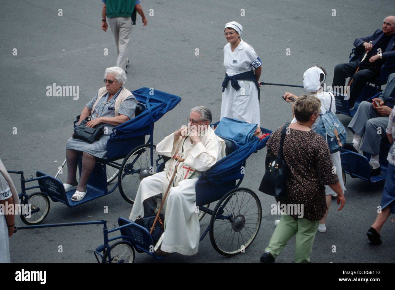 Handicapped pilgrims in wheelchairs en carer heading towards the Divine