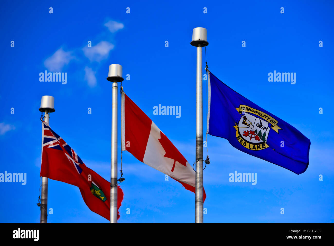 Three flags (Ontario, Canada, Red Lake) on the flag poles in the Norseman Heritage Centre Park in the town of Red Lake, Ontario, Stock Photo