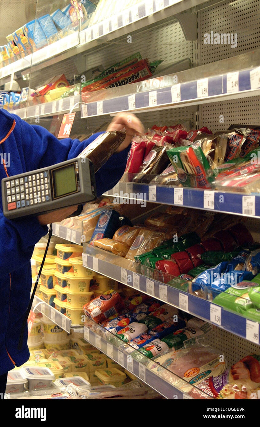 Royalty free photograph of shop worker taking stock/pricing/stacking shelves in convenience store London UK Stock Photo