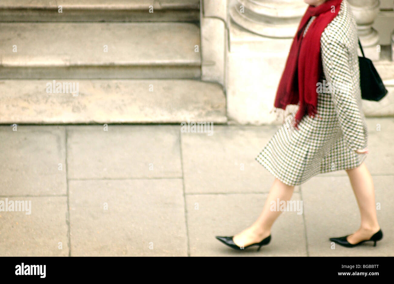 Royalty free photograph of London business woman walking to work with red scarf on the pavement London UK Stock Photo